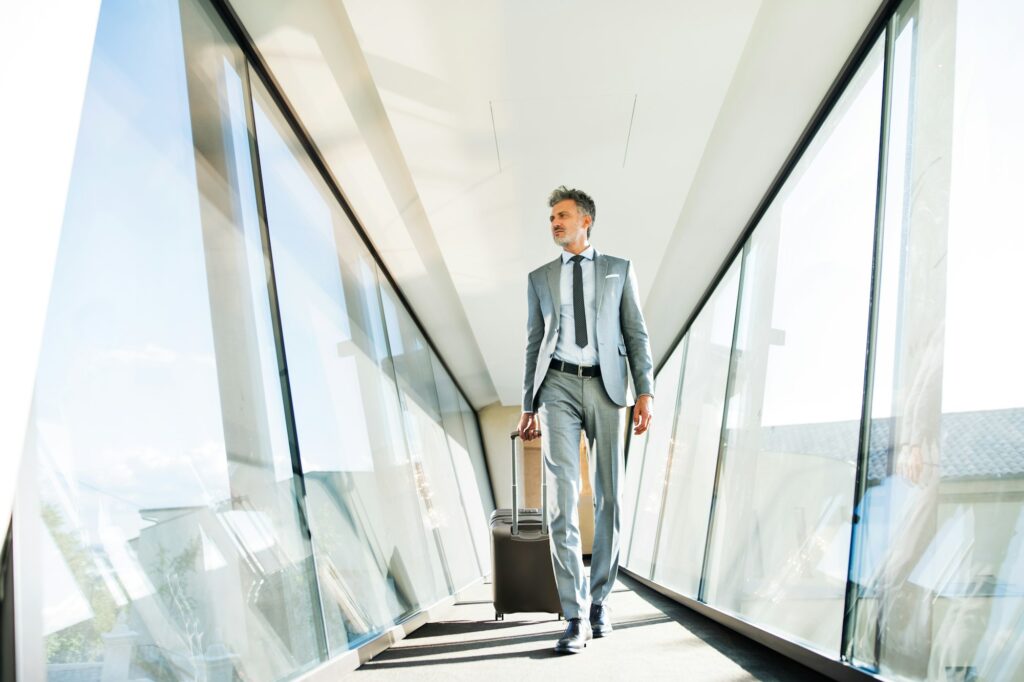 Mature businessman with suitcase travelling.